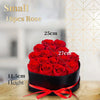 A bouquet of 18 small red roses in a black box with a red ribbon, shown against a light background.