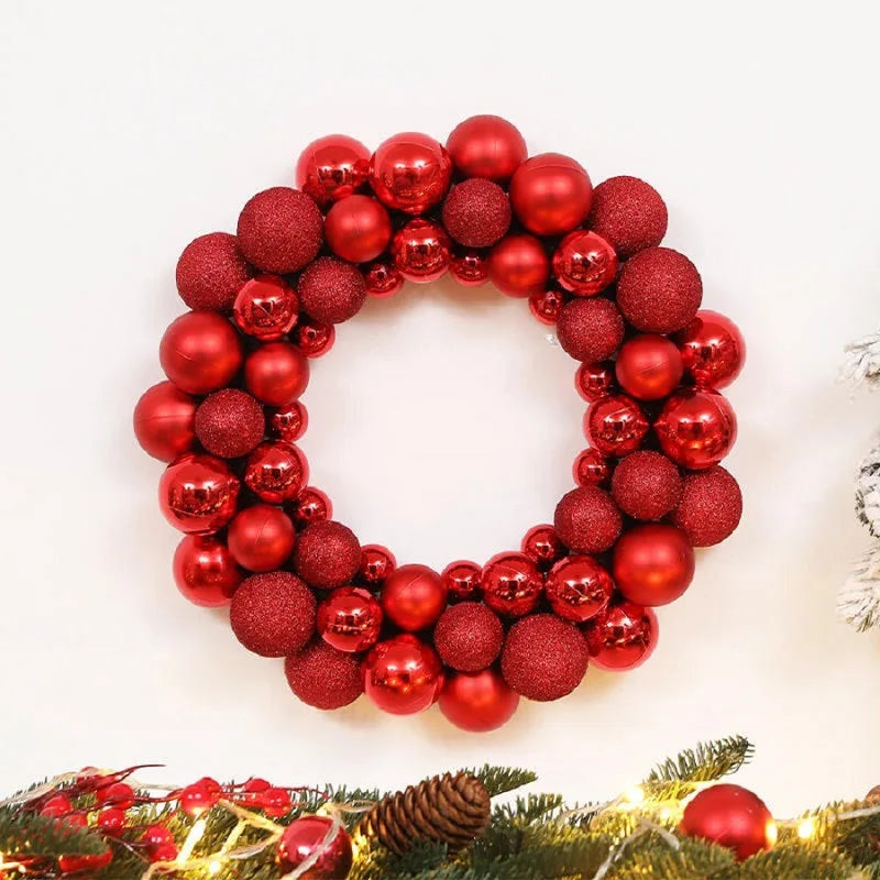 A wreath made of shiny red and bronze glitter Christmas balls on a green branch with lights.