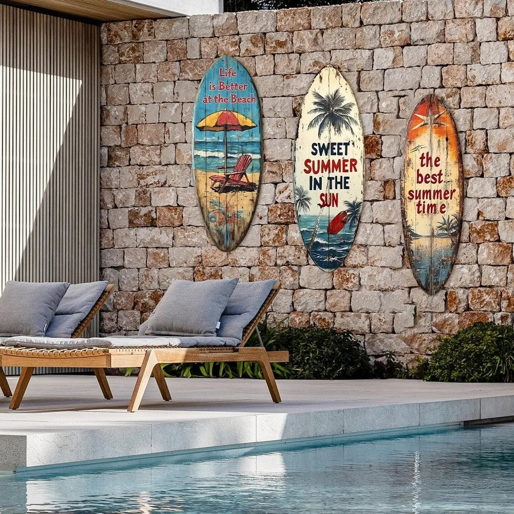 Decorative wooden surfboard wall art featuring tropical scenes and text mounted on a stone wall beside a pool