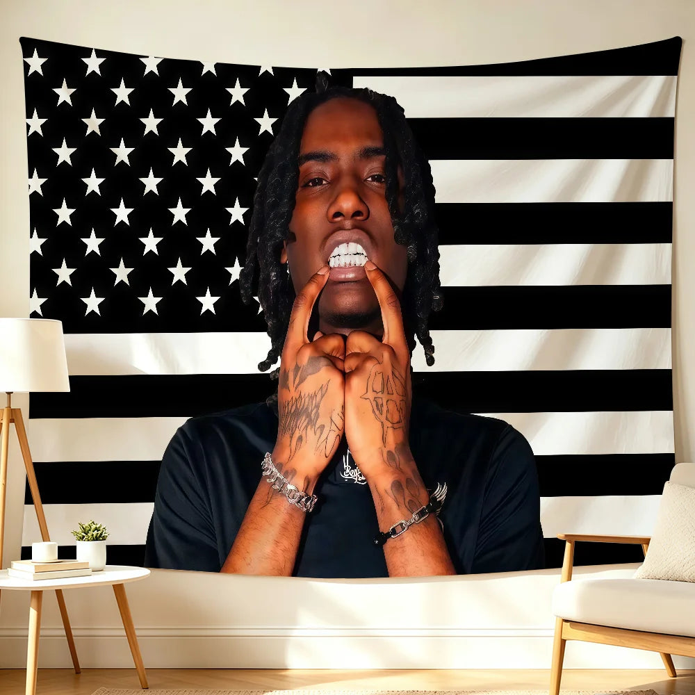 A man with dreadlocks looks directly at the camera against an American flag backdrop featuring stars and stripes.
