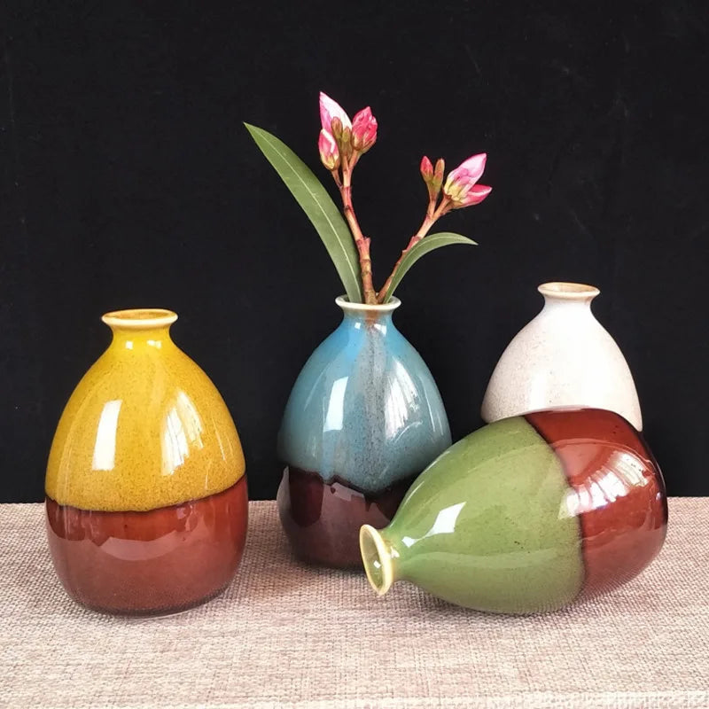 Eine Ansammlung handbemalter Keramikblumenvasen in verschiedenen Gelb-, Blau- und Grüntönen auf einer hellen Oberfläche.