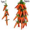 A bundle of 5 artificial orange carrots hanging from a green vine for decoration