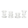 A set of four clear glass candle holders or candlesticks with decorative bases.