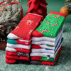 A stack of red, green, and white Christmas socks featuring reindeer and tree patterns, set against a green background.