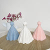 Three silicone molds of wedding dresses in blue, white, and pink on a wooden surface.