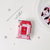 A red cartoon milk bottle photo keychain with a silver clasp and a decorative card on a white background.