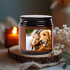A glass jar candle with a photo of a woman and a dog inside, resting on a wooden slice.