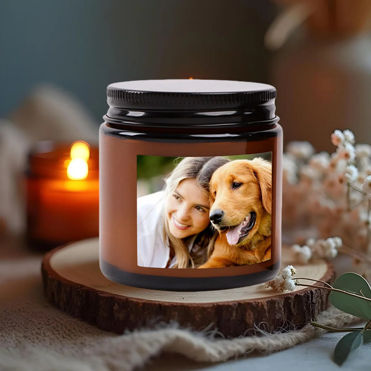A glass jar candle with a photo of a woman and a dog inside, resting on a wooden slice.