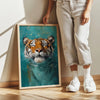 A person stands next to a framed painting of a tiger underwater on a light-colored wall.