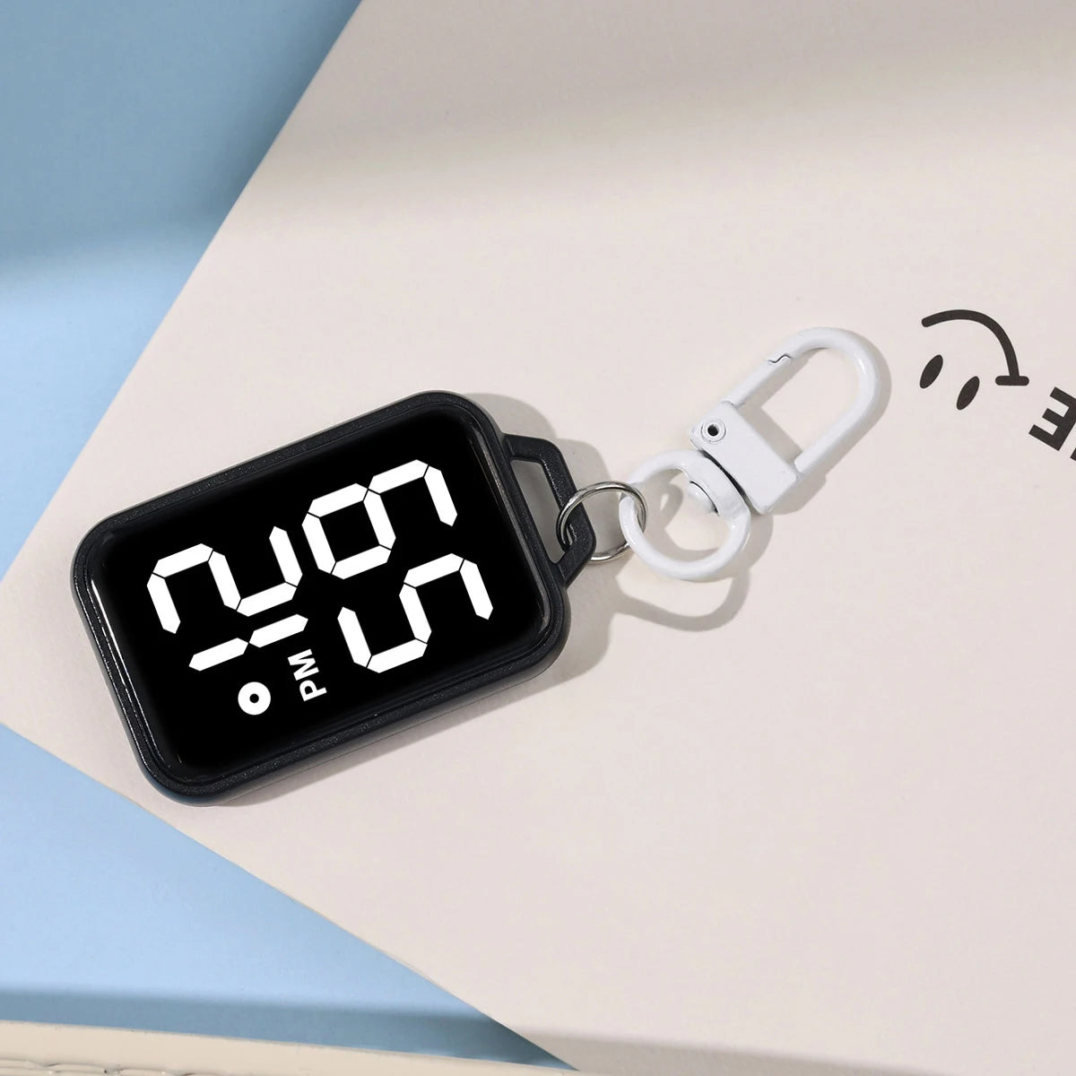 A black LED keychain pocket watch with a digital display showing 2:09 PM on a white surface.