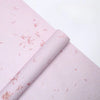 Roll of pink decorative packaging paper with subtle floral patterns