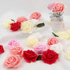 A collection of realistic foam rose flower heads in shades of pink, red, and white arranged on a white surface.