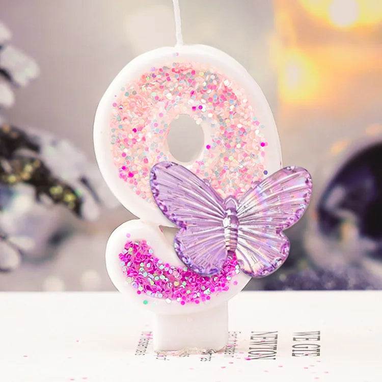 A white candle shaped like the number 8 decorated with pink glitter and a purple butterfly.