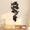 Black silhouette of a dragon wall art mounted on a light beige wall above a wooden shelf.