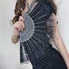 A woman holds an elegant lace folding hand fan with intricate detailing against a light background.