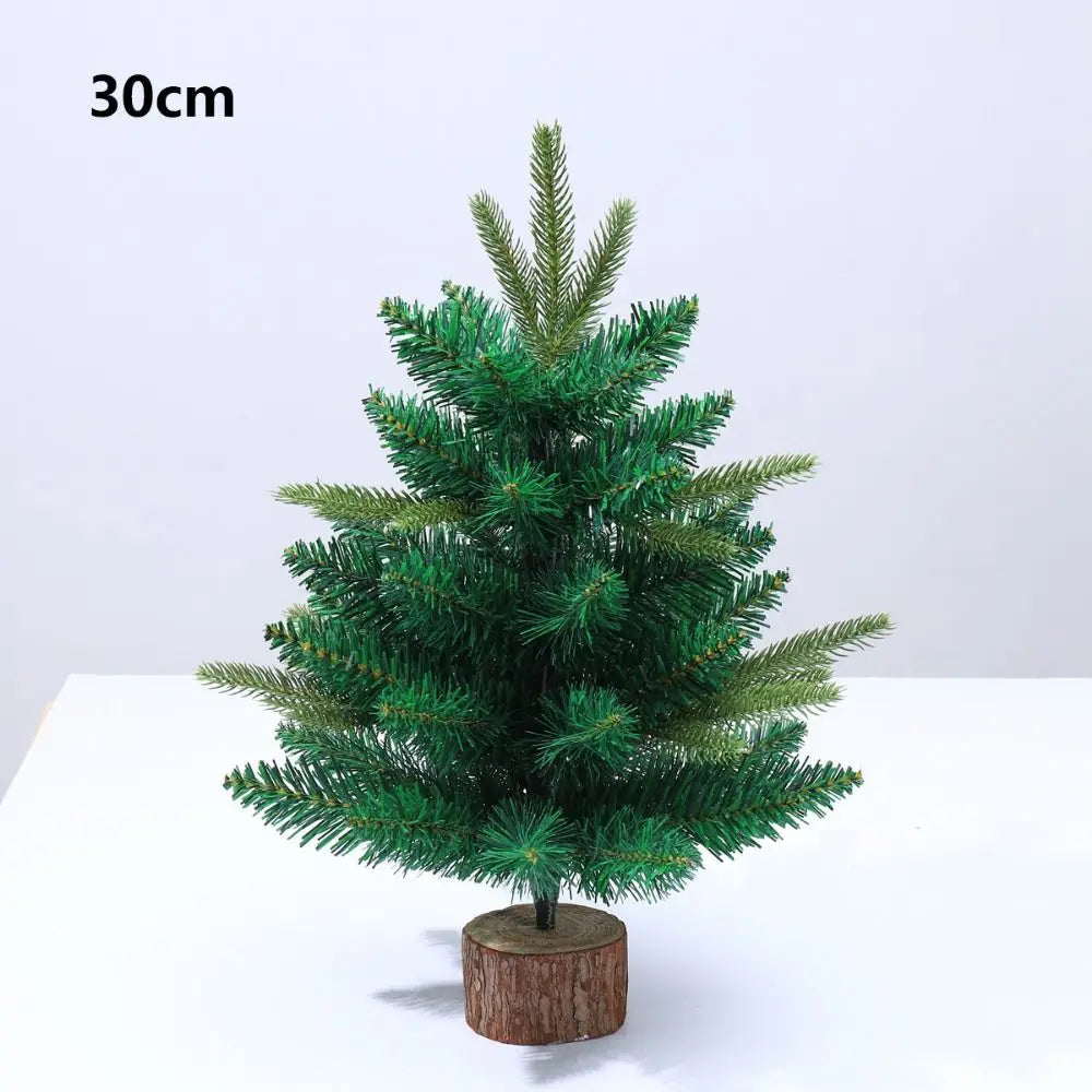 A small, green artificial pine tree with a warm glow displayed on a wooden base.