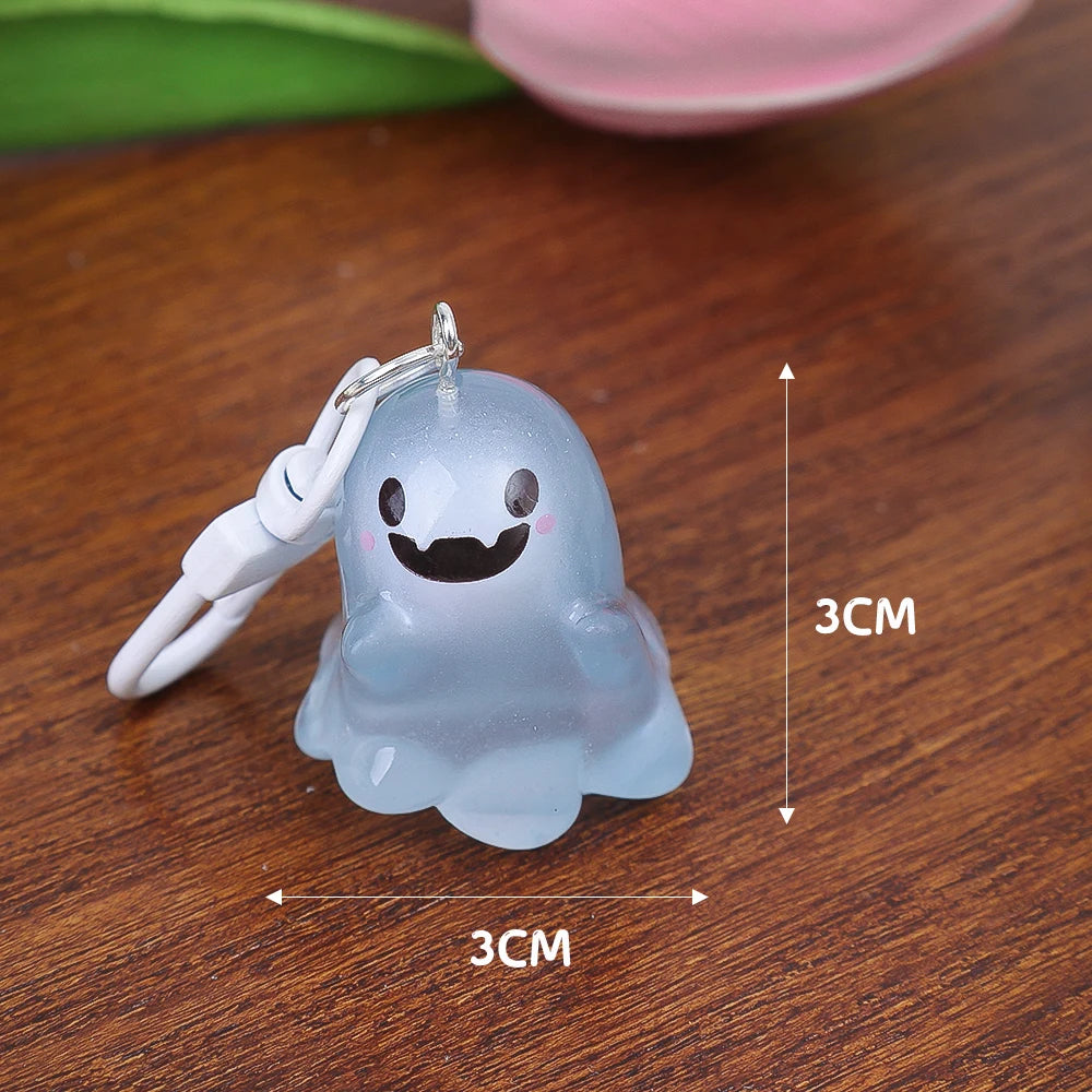 A translucent blue ghost keychain with a smiling face is shown on a wooden surface.