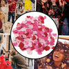 Close-up of pink and red heart-shaped sequins confetti being thrown in the air during a celebration.