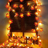 String lights shaped like maple leaves illuminate a wooden slatted window for indoor or outdoor decoration.