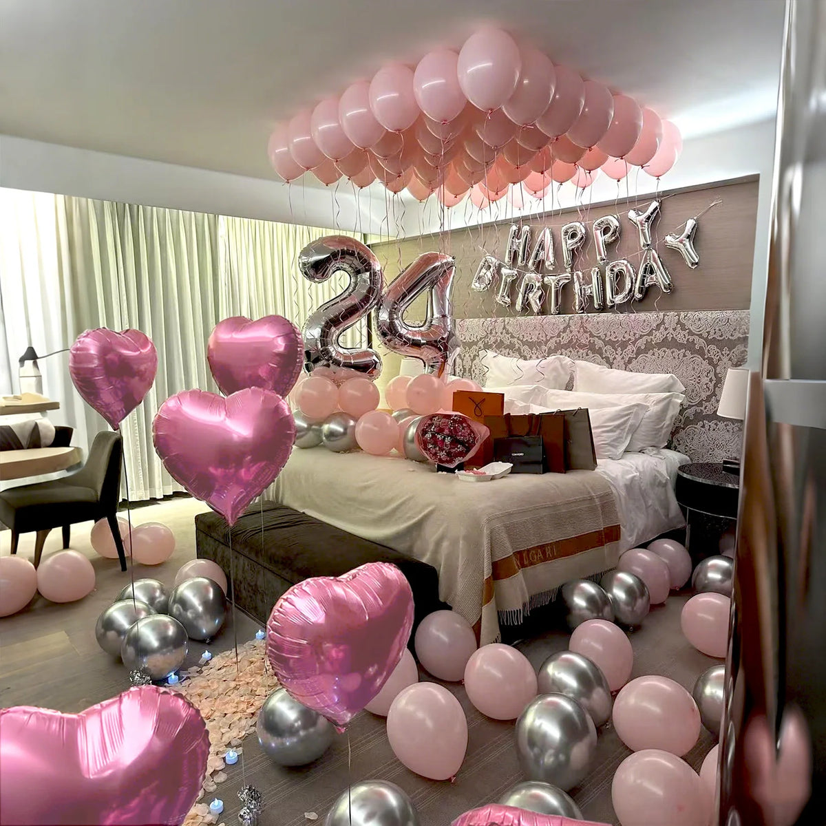 A pink and silver balloon decoration set featuring balloons and a sign for a happy birthday celebration.