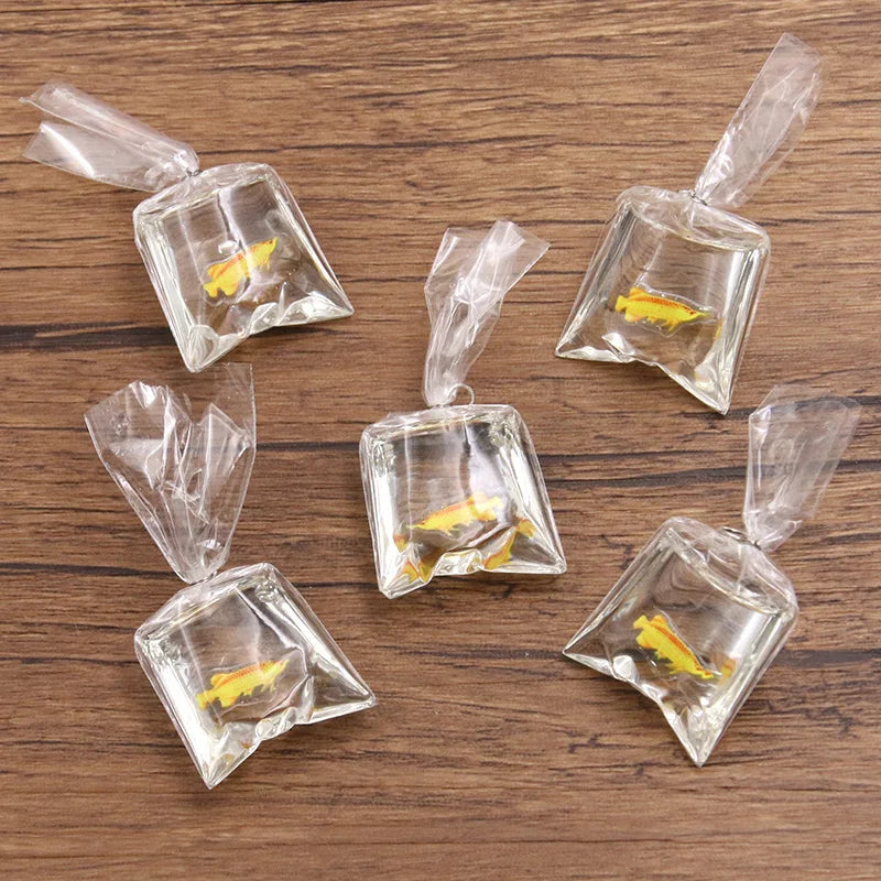 Un set de colgantes de resina transparentes con forma de pez payaso, empaquetados en pequeñas bolsas de plástico para hacer j