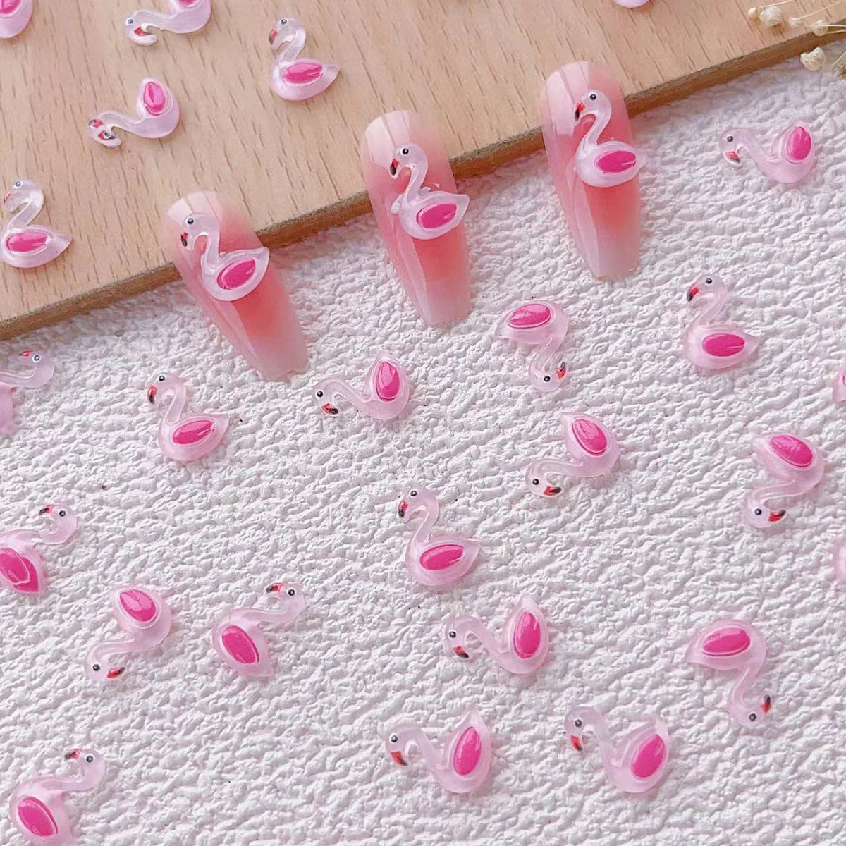 Una colección de 50 aderezos de uñas en forma de tortuga mini rosa y blanco esparcidos sobre una superficie blanca texturizad