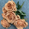 A bouquet of nine realistic silk roses in a soft peach or tan color against a gray background.