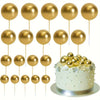 A collection of gold and silver foam ball cake toppers on sticks for party decorations