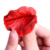 A hand holds a vibrant red silk rose petal, folded and layered, for decoration.