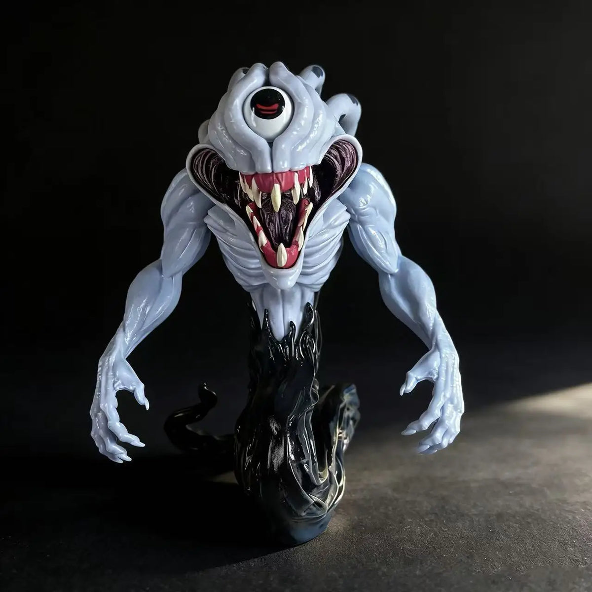 A highly detailed white and gray figurine of a monstrous, snarling creature with glowing red eyes and black tendrils.