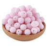 A pile of pink textured resin beads for jewelry making in a wooden bowl.