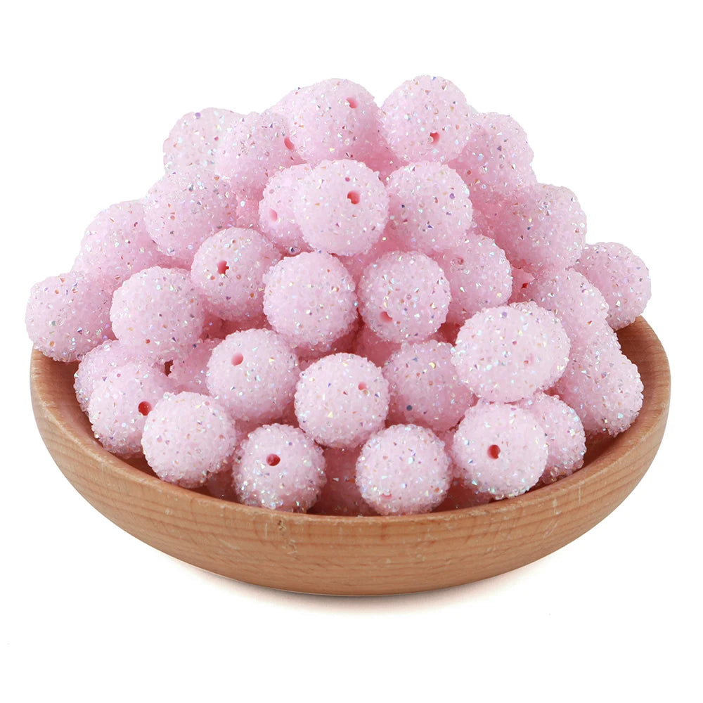A pile of pink textured resin beads for jewelry making in a wooden bowl.