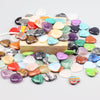 A collection of heart-shaped amethyst crystal stones in various colors scattered on a wooden surface.