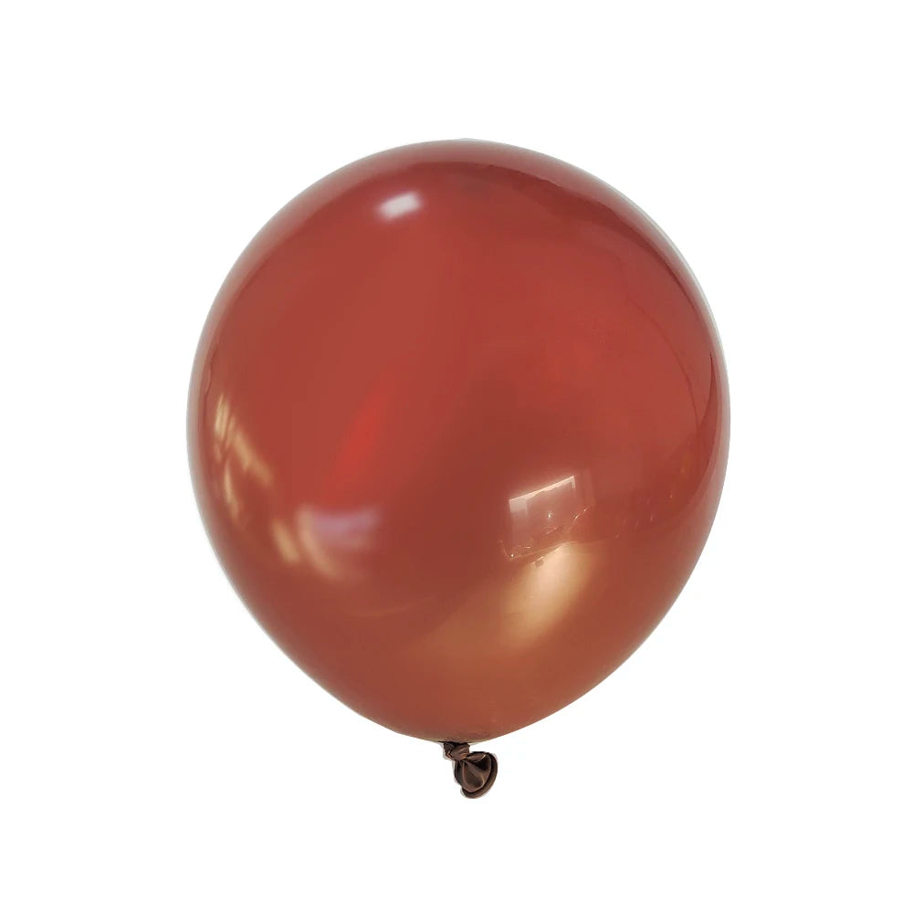 A single matte reddish-orange latex balloon floating against a white background.