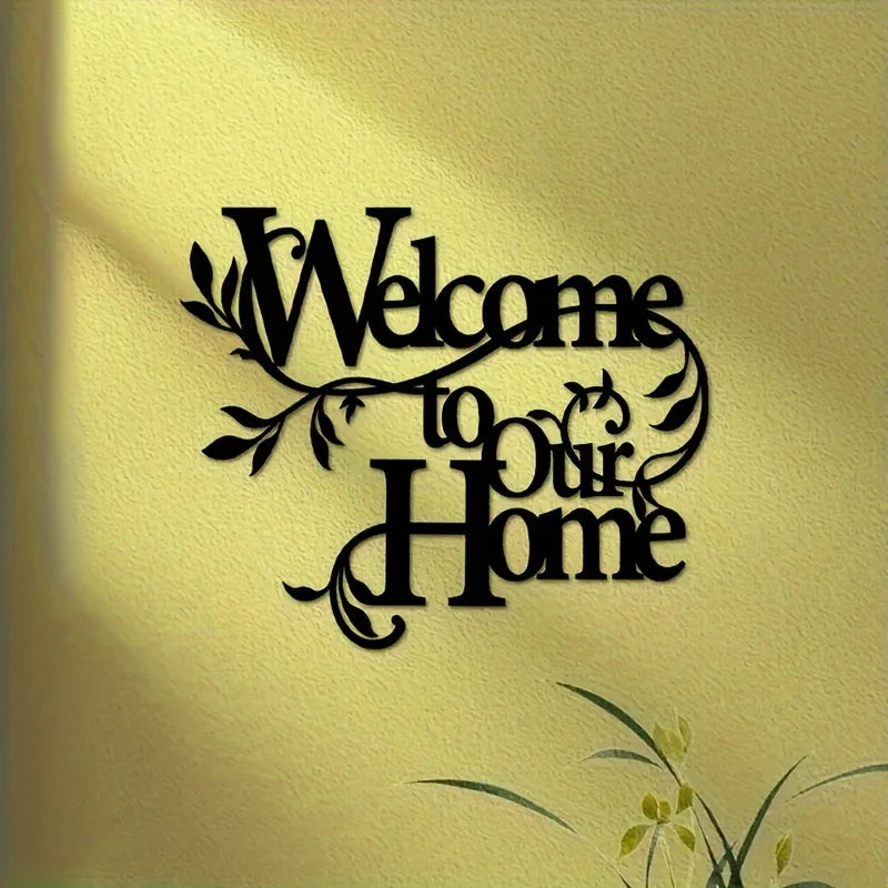 A black metal script sign on a light yellow wall that reads Welcome to Our Home