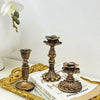 A vintage resin wall sconce candle holder with an ornate bronze base rests on a gold-framed tray next to a book.