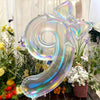 A large, iridescent, transparent number balloon shaped like the number 9 is displayed with floral arrangements.