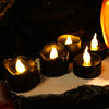 A collection of black LED candles with a warm white glow resting on a light surface.