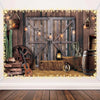 A rustic western backdrop featuring a wooden barn door, hay bales, and decorative string lights.