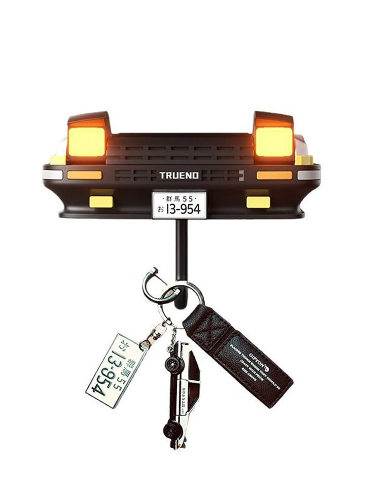 A black classic car headlight key holder with illuminated LED lights and attached keys.