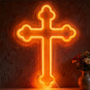 A glowing orange neon cross wall sign mounted on a textured stone wall next to a vase of flowers.