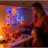 A woman and a child are decorating a kitchen counter with Halloween LED night lights and pumpkins.