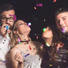 Group of four people looking up and blowing on glow in the dark necklaces and lanyards