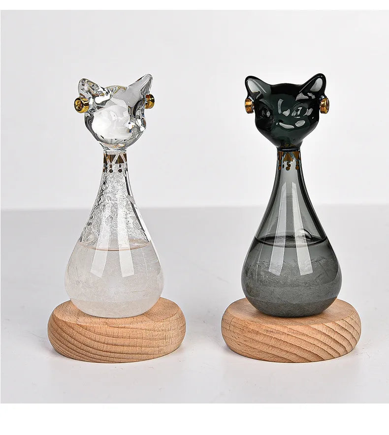 A glass bottle decoration shaped like a cat, featuring a clear and dark green body on a wooden base.