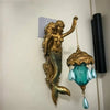A vintage bronze resin sculpture of a mermaid with flowing hair and a glass lamp pendant hanging from her tail.
