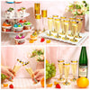 A display of elegant disposable plastic champagne flutes and various food items, including fruit and desserts.
