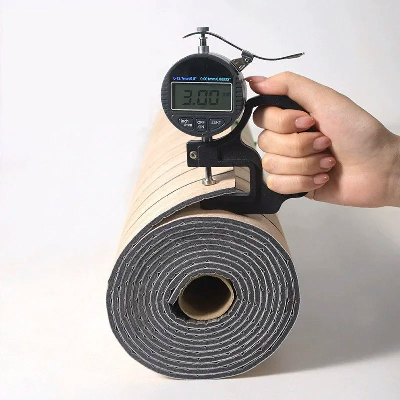 A hand holds a digital measuring tool next to a roll of 3D wood grain self-adhesive wallpaper.