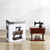 A vintage miniature sewing machine is displayed on a wooden box, suggesting a retro music box product.