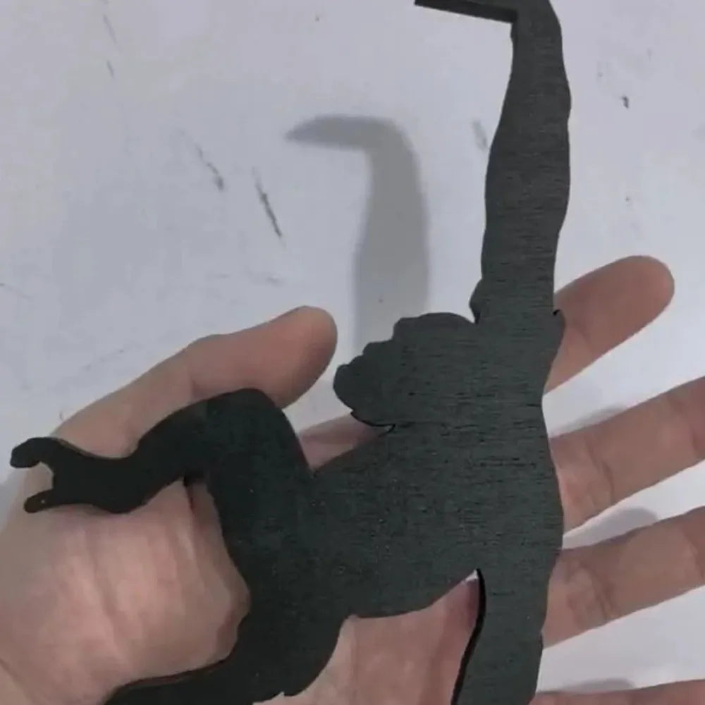 A hand holds a black, monkey-shaped storage hook with a banana design.