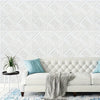 A white upholstered sofa with a light blue throw blanket and a patterned white wall panel background.